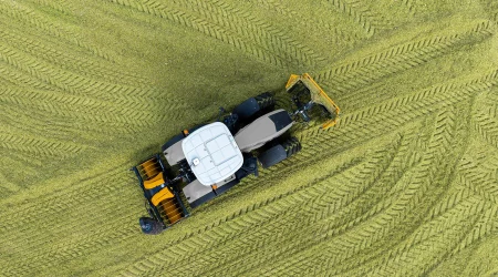 MAMMUT maïsschuif met kuilrol en kantverdichter op de trekker, zijvleugels ingeklapt en ingezwenkt